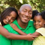 african american father hugging his daughters