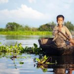 cambodian boy traveling by boat in his floating village e1619245554550