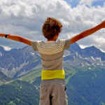 child on the mountain top with arms up 1