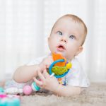 cross eyed baby playing with a toy