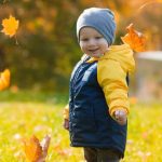 cute little boy playing with maple leaves outdoors e1619160456264