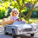 little adorable toddler girl driving big vintage toy car