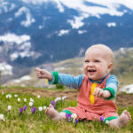 little baby playing with crocus flowers in the alps 1