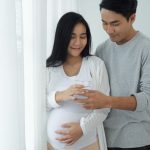 man handing a pregnant woman a glass of water