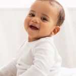 portrait of african baby toddler smiling sitting on bed indoor e1620989351793