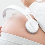 pregnant mother with headphones playing music for her unborn child