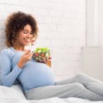 pregnant woman eating salad in bed