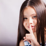 pretty little hispanic girl gesturing to keep it quiet 1