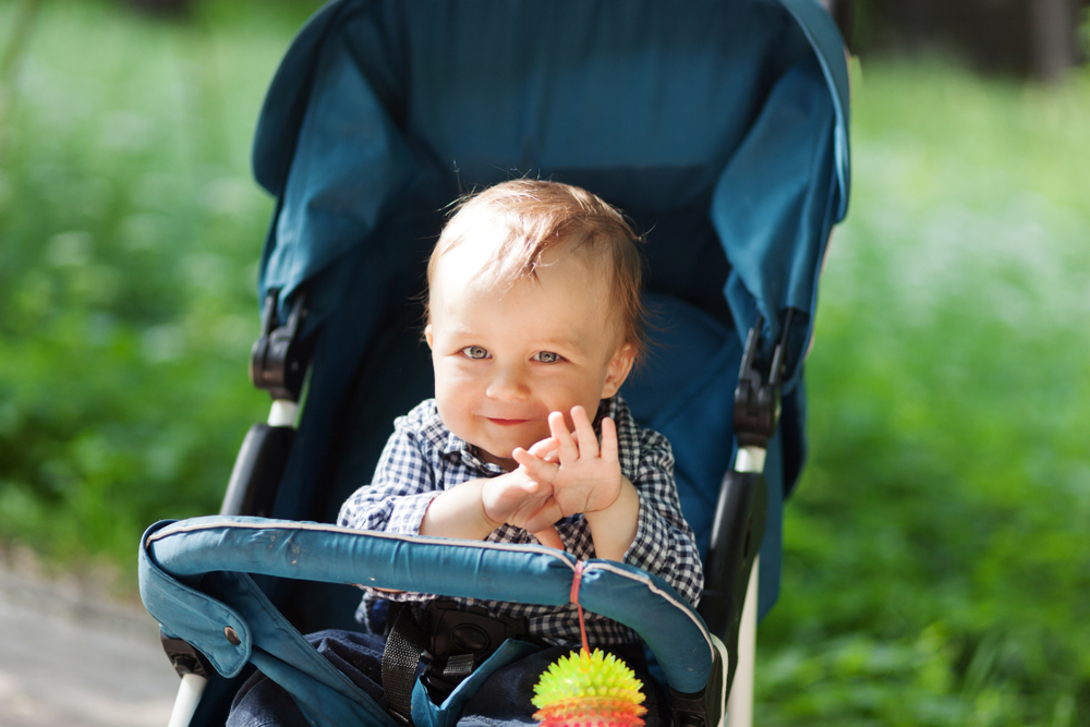 smiling baby in a teal stroller