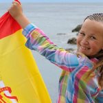 teen girl with spanish flag on the sea e1618901523661