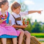 two kids in traditional bavarian costumes in wheat field e1619186665507