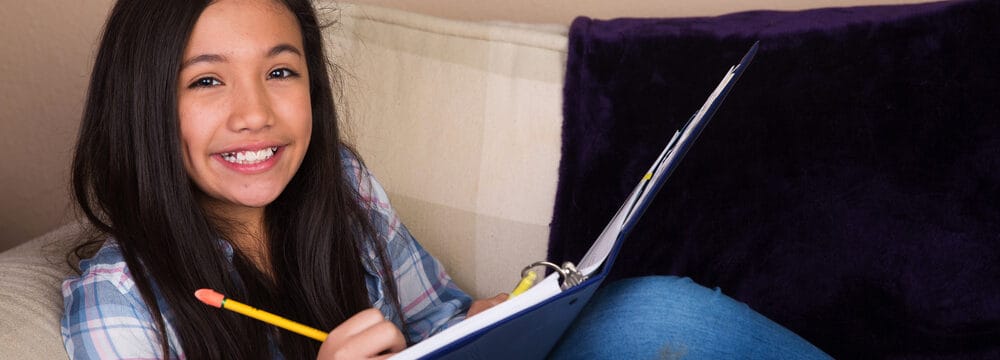 young hispanic girl doing homework on the couch e1619677694241